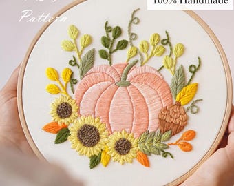 May include: Hand-stitched embroidery art featuring a peach-colored pumpkin surrounded by sunflowers, leaves, and a pinecone. The design is set in a wooden embroidery hoop. The text "No AI Used 100% Handmade" is visible.