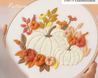 May include: Embroidered fall-themed hoop art featuring two white pumpkins surrounded by orange, yellow, and brown floral accents. The text "PDF Pattern", "No AI Used 100% Handmade", and "YouTube video tutorial" are visible.