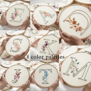 Op de afbeelding: Een verzameling geborduurde bloemenletterontwerpen op ronde hoepels. Elke letter is versierd met kleurrijke bloemstukken. De afbeelding toont 8 kleurenpaletten en presenteert een verscheidenheid aan gepersonaliseerde borduuropties.