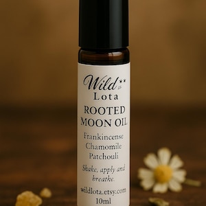 May include: A small, brown glass bottle with a black cap, labelled "Wild Lota ROOTED MOON OIL." The label lists ingredients: Frankincense, Chamomile, and Patchouli. The text "Shake, apply and breathe" is also included. The bottle is 10ml.