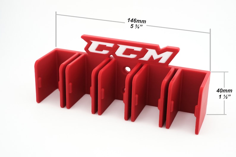 Puede incluir: Porta palos de hockey de pl&aacute;stico rojo con el logotipo de CCM en blanco. El porta palos tiene seis ranuras para palos y mide 14,6 cm de ancho y 4 cm de alto.