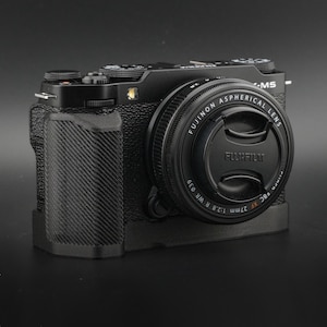 May include: A black Fujifilm X-A5 camera with a Fujinon XC 15-45mm lens. The camera has a textured grip and a silver lens ring.