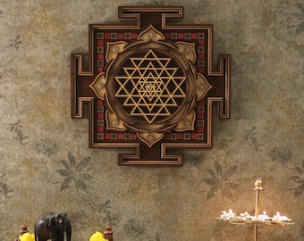 May include: A wooden wall hanging with a brown, gold, and red geometric design. The design is a Sri Yantra, a sacred symbol in Hinduism. The wall hanging is surrounded by a floral patterned wall.