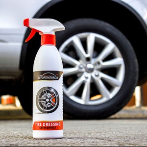 May include: A white bottle of tire dressing with a red spray nozzle. The bottle has a black and white image of a tire and rim on the front. The text on the bottle reads "AUTO RENOVACIA TIRE DRESSING SATIN EFFECT".