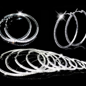 May include: A set of silver hoop earrings with clear rhinestones. The earrings are available in different sizes.