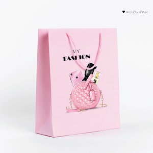 May include: Pink shopping bag with the text "MY FASHION" printed on the front. The bag features a pink quilted handbag with a gold chain strap, sunglasses, a phone, and a bottle of perfume inside.