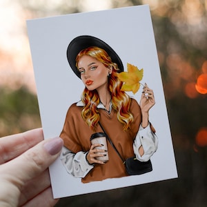 Pode incluir: Uma mulher com cabelo comprido, ondulado e vermelho est&aacute; vestindo um su&eacute;ter marrom, um chap&eacute;u preto e uma camisa branca. Ela est&aacute; segurando uma x&iacute;cara de caf&eacute; e uma folha amarela.