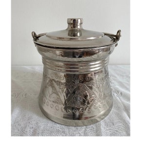 May include: Silver metal container with a lid and two handles. The container has an embossed floral design.