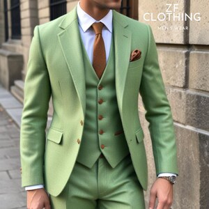 Pu&ograve; includere: Un abito tre pezzi di colore verde chiaro con un gilet e una cravatta marroni. La giacca del vestito ha un fazzoletto da taschino marrone. Il testo "ZF CLOTHING MEN'S WEAR" &egrave; visibile nell'angolo in alto a destra dell'immagine.