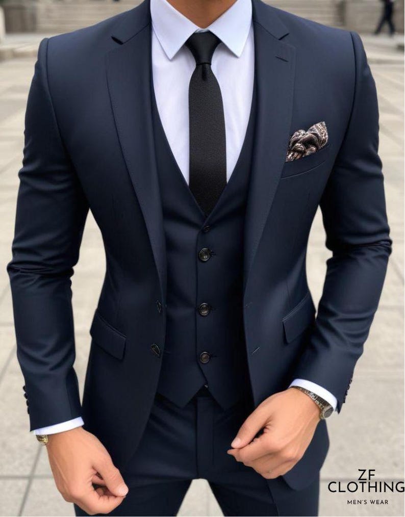 May include: A navy blue three-piece suit with a black tie and a patterned pocket square.  The suit jacket has a single button closure and a notched lapel.  The vest has a five-button closure.  The pants have a flat front and a straight leg.