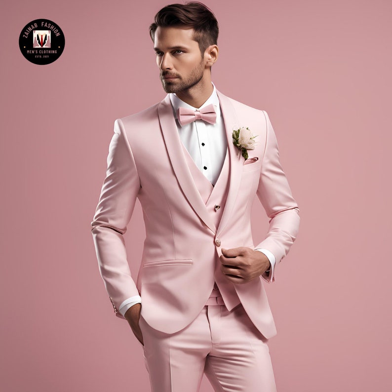 Puede incluir: Un traje de tres piezas de color rosa con camisa blanca y pajarita rosa. El traje tiene un cierre de bot&oacute;n &uacute;nico y un pa&ntilde;uelo de bolsillo con una flor blanca.
