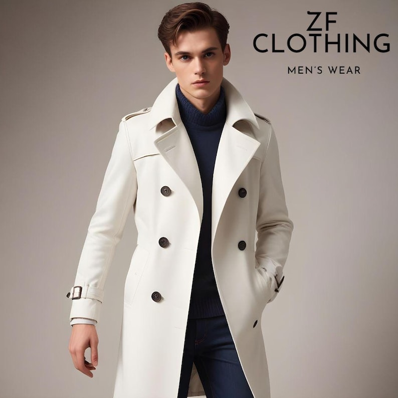 Puede incluir: Un abrigo blanco de gabardina de doble botonadura con cintur&oacute;n y botones marrones. El abrigo tiene un cuello alto y est&aacute; hecho de una tela lisa.  ZF CLOTHING MEN'S WEAR est&aacute; escrito en negro en la parte superior de la imagen.