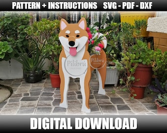 May include: A digital download pattern for a wooden Shiba Inu dog cutout. The dog is brown and white with a pink tongue sticking out. The pattern is available in SVG, PDF, and DXF formats. The image shows the finished product in a garden setting.