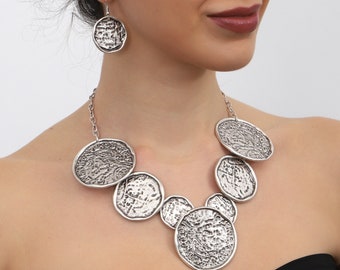 May include: A silver necklace with a chain and multiple round pendants. The pendants have a textured, hammered finish.