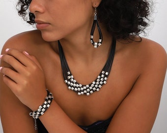 Necklace, bracelet and earrings decorated with silver-plated beads on a black leather strap
