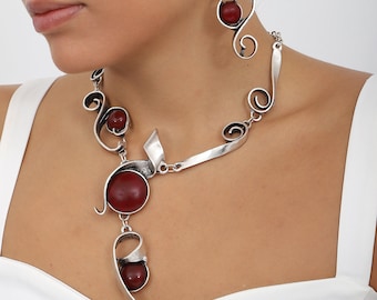 Handgemaakte verzilverde ketting en oorbel bezet met bordeauxrode edelstenen.