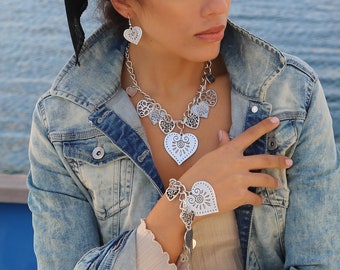 May include: A silver necklace and bracelet with a heart design. The necklace has multiple heart charms, while the bracelet has a larger heart charm.