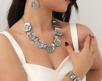 May include: Silver tone jewelry set with a necklace and earrings. The necklace features a chain with multiple round, textured pendants. The earrings are drop earrings with a similar textured design.