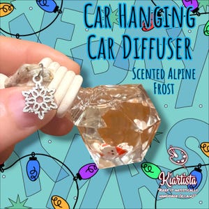 May include: A car hanging diffuser with a clear, faceted container holding small Santa Claus figures. The diffuser is scented with Alpine Frost and has a silver snowflake charm. Text on the image reads "Car Hanging Car Diffuser" and "Kiartista".