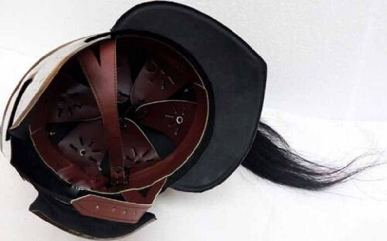 Puede incluir: Un casco medieval con una visera de cuero negro y una larga pluma de crin de caballo negra. El casco est&aacute; hecho de metal y tiene un interior de cuero marr&oacute;n.