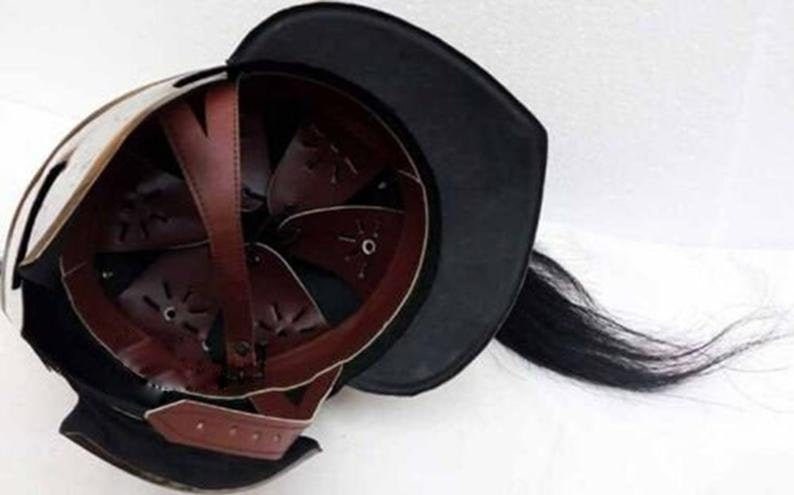 K&ouml;nnte beinhalten: Ein mittelalterlicher Helm mit schwarzem Lederfutter und einer schwarzen Rosshaar-Feder. Der Helm ist aus Metall und hat ein braunes Lederinnere.