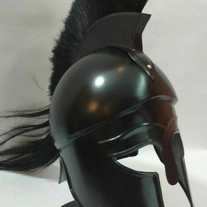 K&ouml;nnte beinhalten: Ein schwarzer spartanischer Helm mit einer schwarzen Rosshaar-Feder. Der Helm steht auf einem schwarzen St&auml;nder.