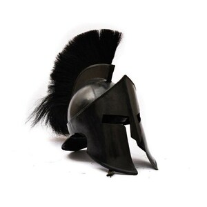 Puede incluir: Un casco espartano negro con una pluma de crin de caballo negra. El casco tiene una m&aacute;scara facial distintiva con una hendidura vertical para los ojos.