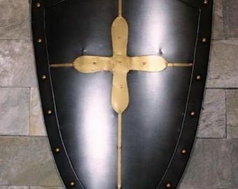 May include: A black metal shield with a gold cross design. The shield has a pointed top and a rounded bottom. It is decorated with metal studs around the edge.