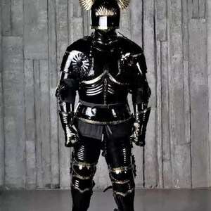 May include: A full suit of black armor with gold accents. The armor includes a helmet with a visor and winged helmet crest. The armor is standing on a gray background.