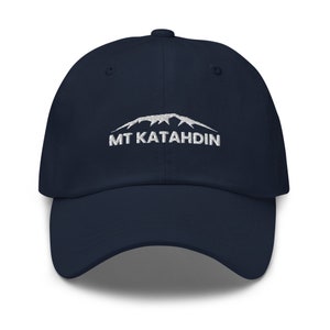 May include: A navy blue baseball cap with a white embroidered mountain range and the text "MT Katahdin".