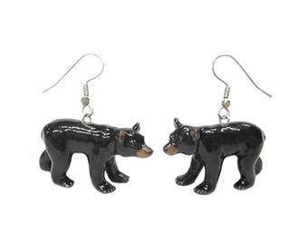May include: A pair of black bear earrings. Each earring features a small, three-dimensional bear figurine with a brown snout and silver-colored ear wires. The bears are in a walking pose.