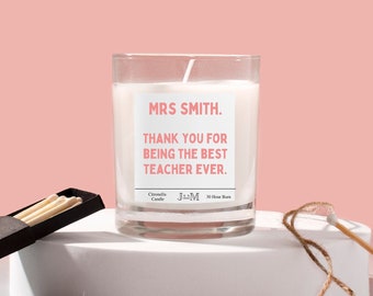May include: A white glass candle jar with a pink label that reads "MRS SMITH. THANK YOU FOR BEING THE BEST TEACHER EVER." The candle is a citronella candle with a 30-hour burn time.
