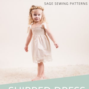 Puede incluir: Un vestido blanco fruncido con un borde de encaje y un lazo en cada tirante. El vestido es para una niña pequeña y está etiquetado como un patrón de costura para principiantes. El texto de la imagen dice "Vestido fruncido" y "Nivel de dificultad: Principiante".