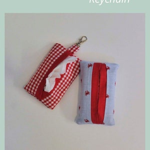 May include: Two handmade travel tissue packs with keychains. One is red and white gingham with a red trim. The other is light blue with red crabs and a red trim. The text on the image reads "TRAVEL TISSUE PACK Keychain" and "SAGE SEWING PATTERNS".