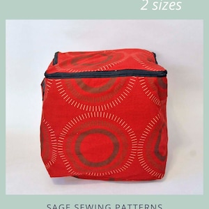 Puede incluir: Cubo de almacenamiento rojo con cremallera y un patrón de círculos marrones y blancos. El cubo está disponible en dos tamaños.  "Zippered Storage Cubes" y "2 sizes" están impresos en la imagen.