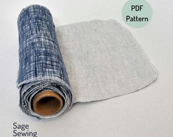 Könnte beinhalten: Gerollter Stoff mit blau-weißem Gittermuster, teilweise abgerollt, um einen hellgrauen Stoff freizugeben. Der Text "PDF Pattern" befindet sich in einem grünen Kreis, und "Sage Sewing Patterns" steht darunter. Der Stoff befindet sich auf einer Holzspule.