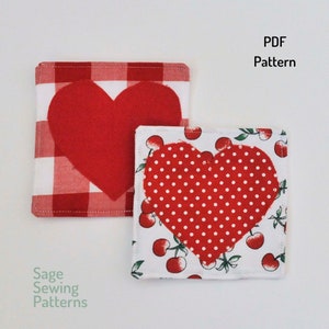 Pode incluir: Dois porta-copos vermelhos em forma de coração, um com um padrão xadrez vermelho e branco e o outro com um padrão de bolinhas vermelhas e brancas. Os porta-copos estão sobre um fundo branco. Padrão PDF.