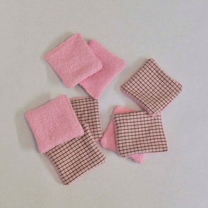 K&ouml;nnte beinhalten: Sechs wiederverwendbare Abschminkpads in Rosa und Braun. Die Pads bestehen aus zwei Stoffschichten, eine rosa und eine braune mit Karomuster.