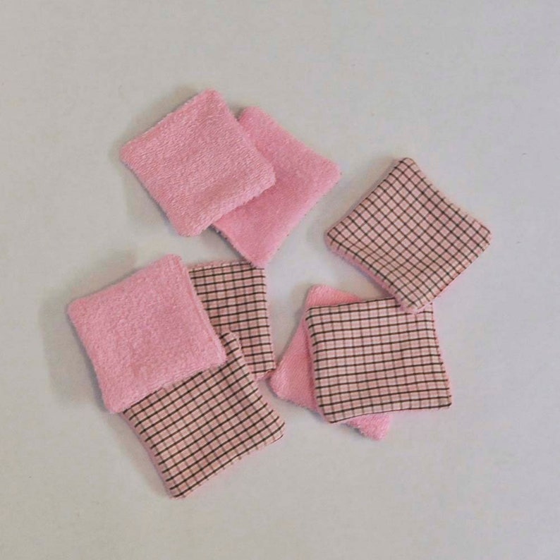 K&ouml;nnte beinhalten: Sechs wiederverwendbare Abschminkpads in Rosa und Braun. Die Pads bestehen aus zwei Stoffschichten, eine rosa und eine braune mit Karomuster.
