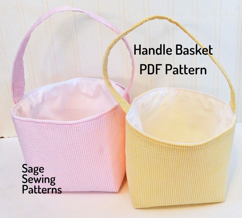 May include: Two fabric handle baskets, one pink and one yellow, with white gingham patterns. The baskets are empty and have a white lining. The text "Handle Basket PDF Pattern" is printed above the baskets. The text "Sage Sewing Patterns" is printed below the pink basket.