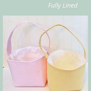 May include: Two fabric baskets with handles, one pink and one yellow, both with white gingham patterns. The baskets are fully lined and have a white fabric interior. The text "HANDLE BASKET Fully Lined" is at the top of the image. The text "SAGE SEWING PATTERNS" is at the bottom of the image.