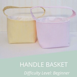 May include: Two fabric handle baskets, one yellow and one pink, with white gingham patterns. The baskets are on a white background.  HANDLE BASKET Difficulty Level: Beginner