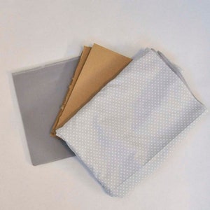 May include: Three pieces of fabric: a gray fabric with a white border, a brown fabric, and a gray fabric with white polka dots.