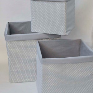 May include: Three gray fabric storage boxes with white polka dots. The boxes are stacked on top of each other.