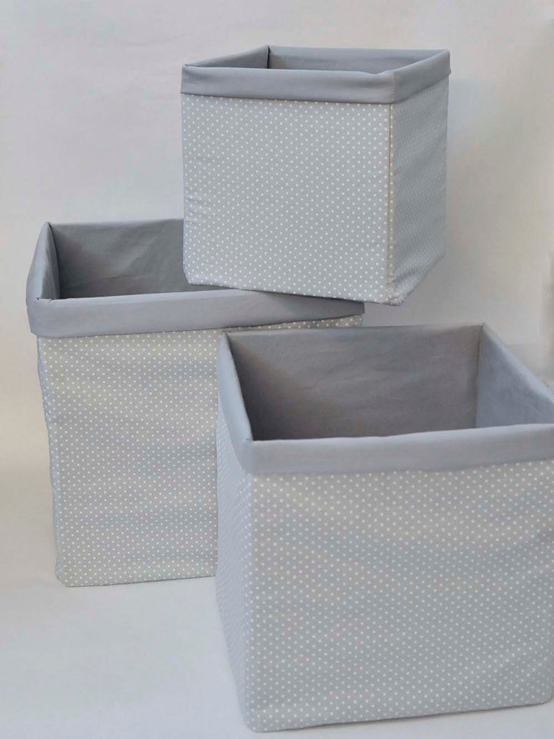 May include: Three gray fabric storage boxes with white polka dots. The boxes are stacked on top of each other.