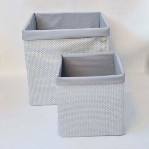 May include: Two gray fabric storage bins with white polka dots. The larger bin is stacked on top of the smaller bin.
