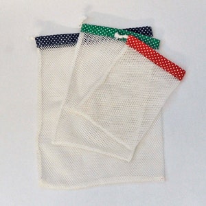 May include: Set of three white mesh produce bags with different colored trim. The bags have a navy blue, green, and red trim with white polka dots.