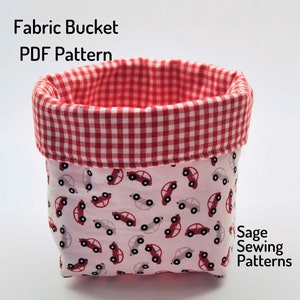 Puede incluir: Un cubo de tela de cuadros rojos y blancos con fondo blanco e impresi&oacute;n de coches rojos. El cubo est&aacute; hecho de tela y es un patr&oacute;n de costura. El texto "Fabric Bucket PDF Pattern" y "Sage Sewing Patterns" es visible en la imagen.