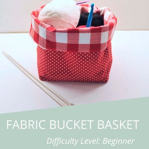 Puede incluir: Una cesta de cubo de tela de cuadros rojos y blancos con lunares blancos. La cesta est&aacute; llena de hilo y agujas de tejer. El texto "FABRIC BUCKET BASKET" y "Difficulty Level: Beginner" se muestra sobre un fondo verde claro.