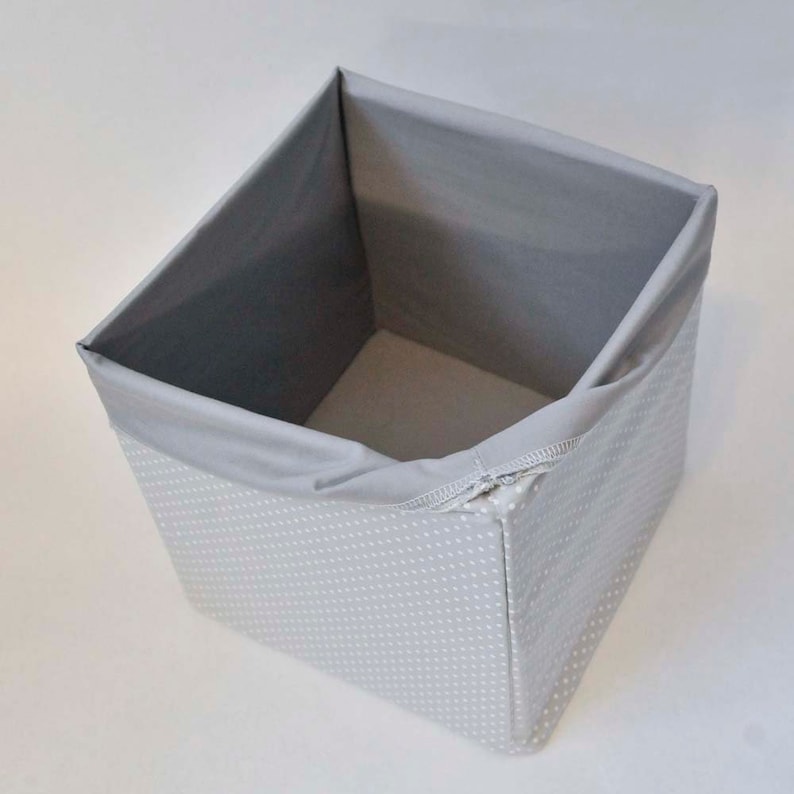May include: A gray storage cube with white polka dots. The cube is made of fabric and has a zipper closure.